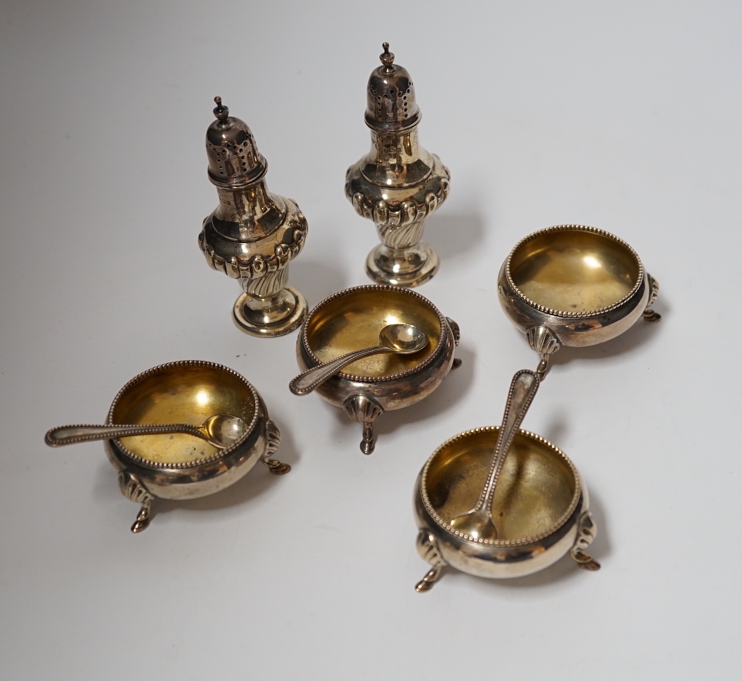A set of four late Victorian silver bun salts by Hukin & Heath, with four matched spoons and a pair of silver pepperettes